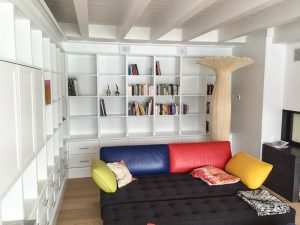 weisses deckenhohes Bücherregal mit dunklen Sofa