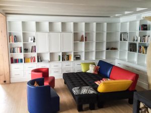 weisses deckenhohes Bücherregal mit bunten Sofa