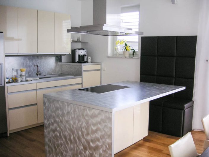 Küche mit glänzend lakierten Fronten und schwarzer Sitzbank mit Leder Arbeitsfläche Alu